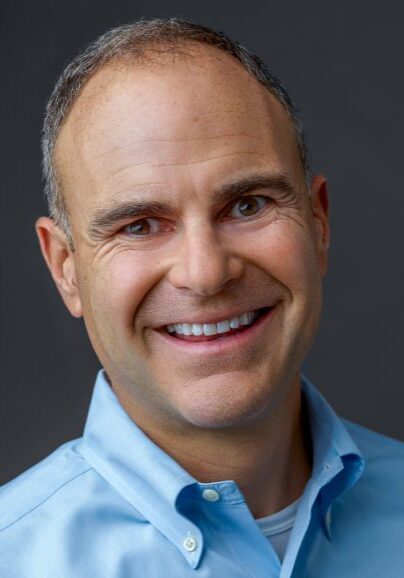 Smiling man in blue collared shirt.