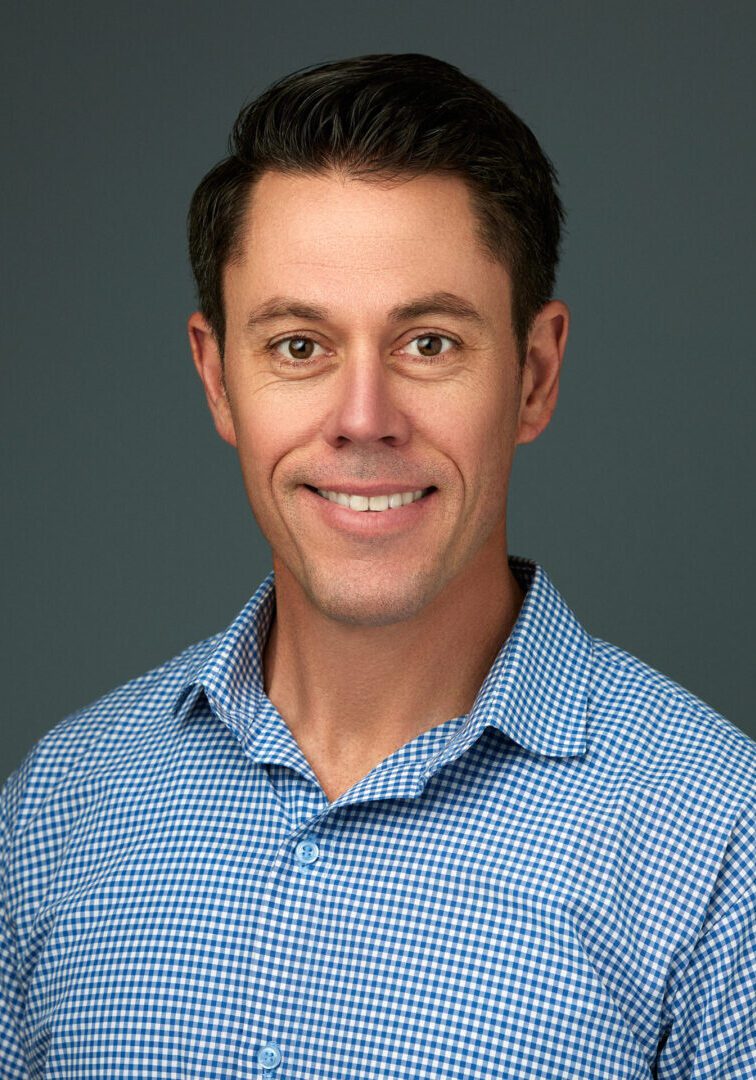 Smiling man in blue checkered shirt.