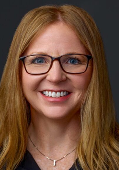 Smiling woman with glasses and long hair.